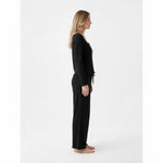 Side view of a woman wearing a black JOANNA FASHION ribbed long sleeve lounge set with lettuce-edge trim.