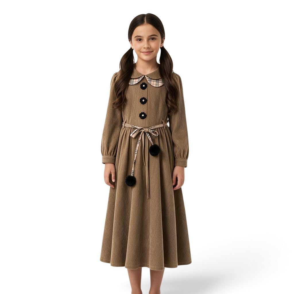 A girl wearing a JOANNA FASHION brown long-sleeve dress with a plaid Peter Pan collar, floral buttons, and pom-pom belt.