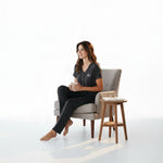 Woman wearing a charcoal grey JOANNA FASHION button-down pajama set while sitting in a cozy armchair with a mug.