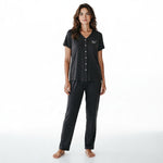A woman wearing a JOANNA FASHION charcoal grey two-piece pajama set with a V-neck button-down top and matching pants.