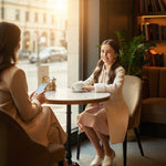 JOANNA FASHION cream long formal coat with faux-fur cuffs and floral embroidery worn by a girl in a cafe
