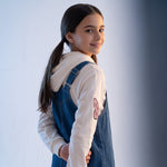 JOANNA FASHION girl wearing a blue denim pinafore dress over a white hoodie with pink butterfly sleeve graphics