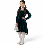JOANNA FASHION girl in a deep emerald green velvet high-low dress with sparkling bodice and pearl-trimmed neckline.