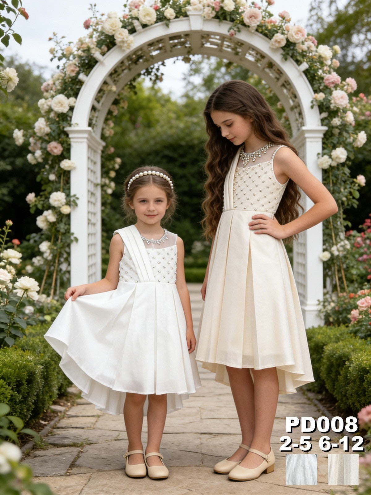 Two girls wearing JOANNA FASHION elegant ivory formal dresses with pearl beadwork and high-low hems in a garden.