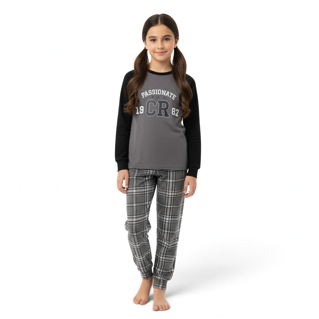 A young girl wearing a JOANNA FASHION two-piece pajama set with a grey raglan top and grey plaid bottoms.
