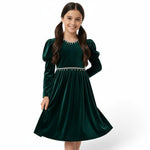 JOANNA FASHION girl wearing a dark green velvet dress with puff sleeves and pearl-style trim at the neckline and waist