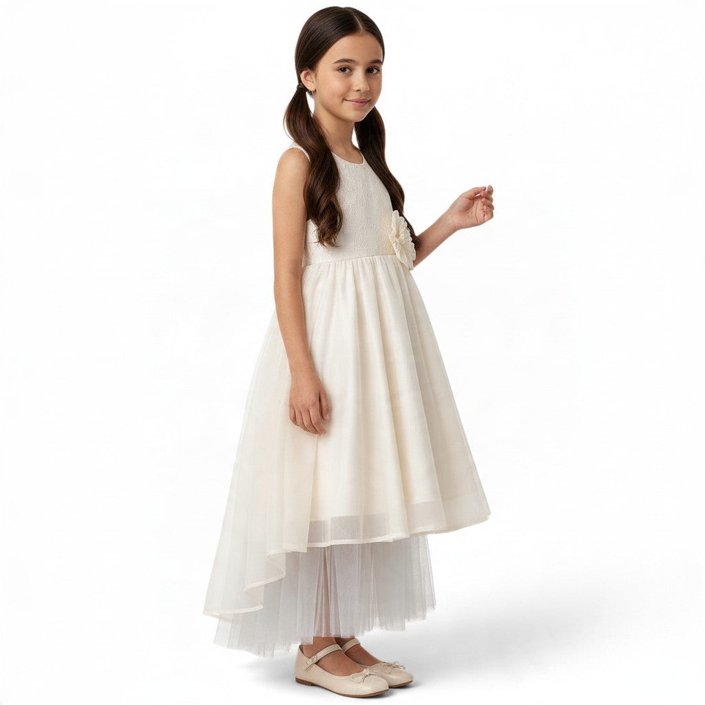 A young girl wearing a JOANNA FASHION ivory sleeveless formal dress with a lace bodice, floral waist, and tulle skirt.