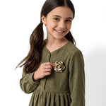 JOANNA FASHION girl wearing an olive green long sleeve corduroy dress with a gold rose floral appliqué on the chest