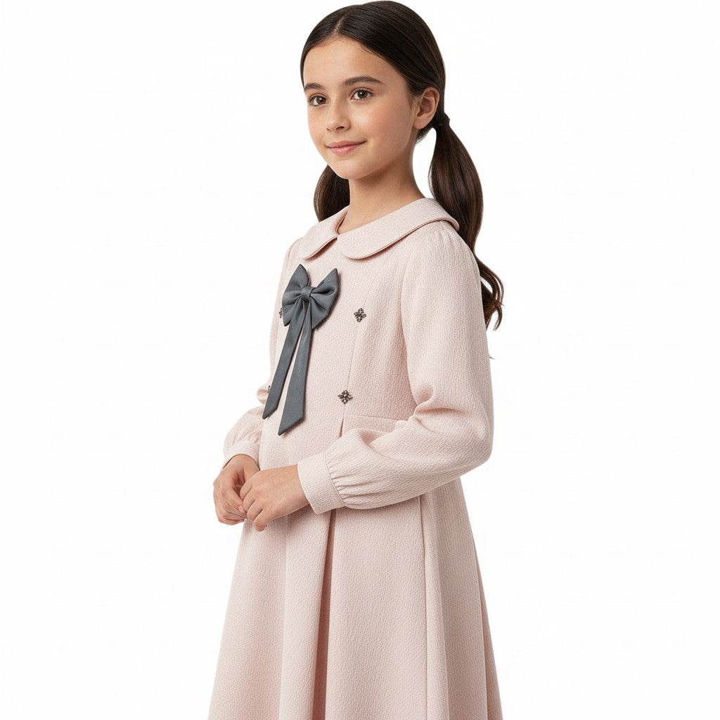 JOANNA FASHION girl wearing a pale pink long-sleeve dress with a Peter Pan collar, grey bow, and textured fabric.
