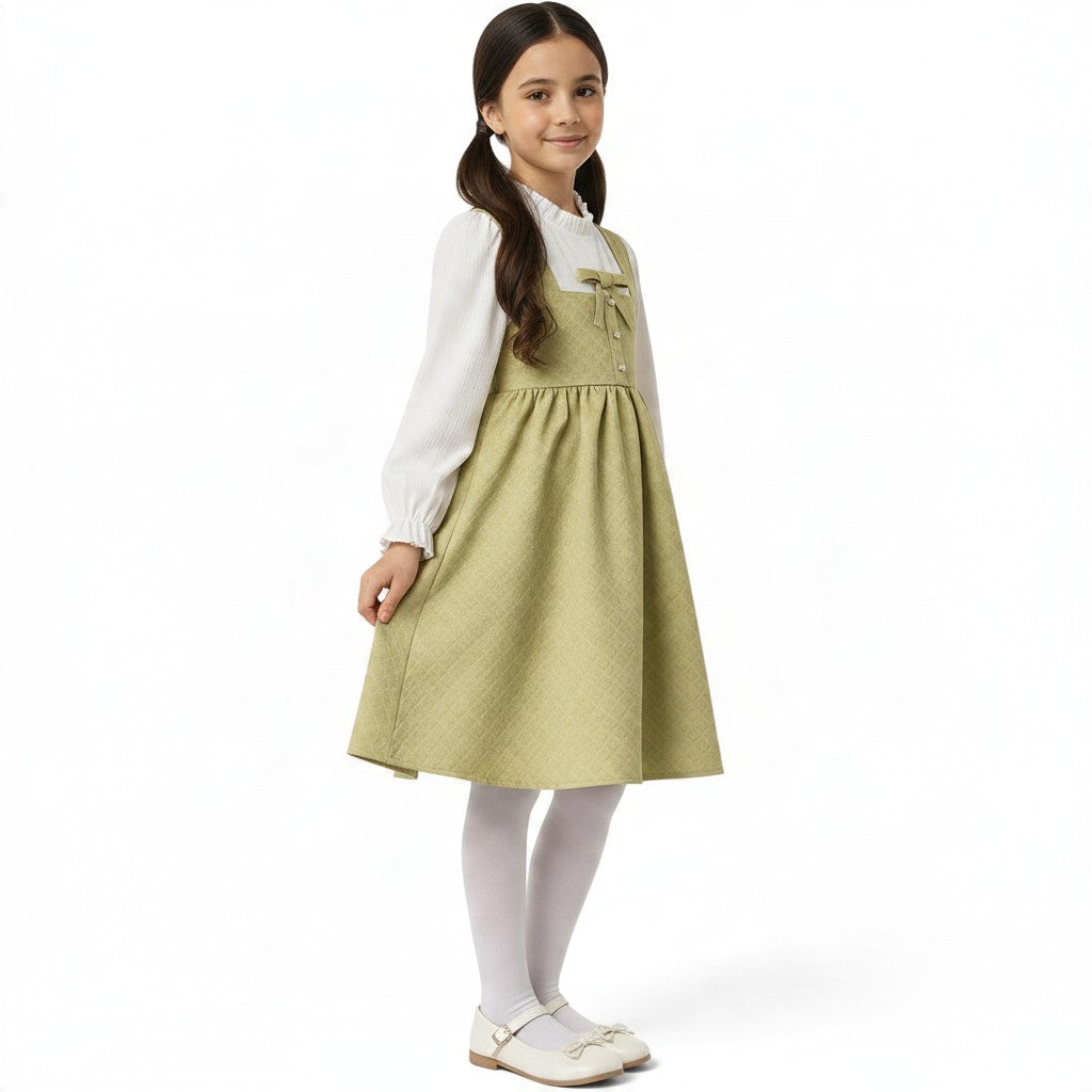 JOANNA FASHION sage green quilted pinafore dress with bow detail worn by a young girl with a white blouse and tights.