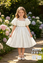 JOANNA FASHION white flower girl dress with floral applique bodice, puff sleeves, and rhinestone belt in a garden