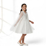 JOANNA FASHION white tulle flower girl dress with floral embroidery, beadwork, and an attached sheer cape with bows.