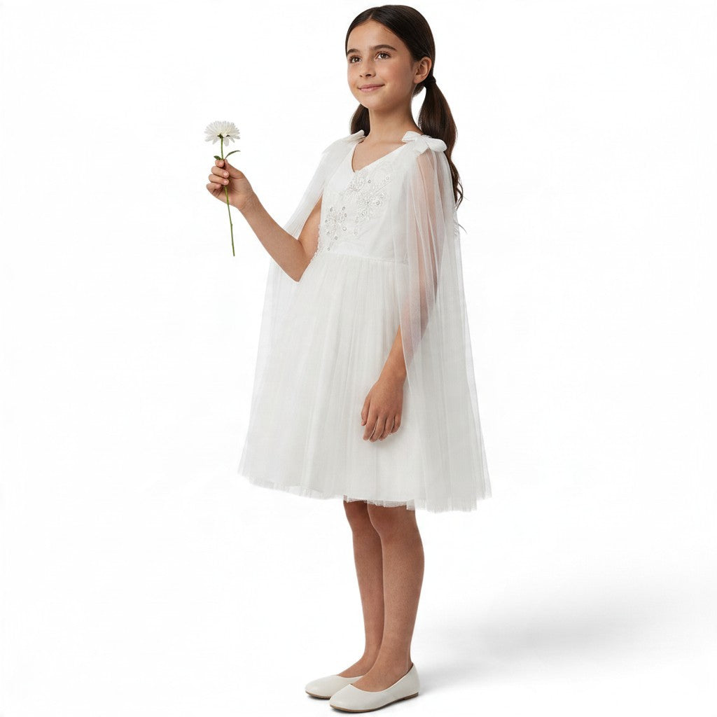 JOANNA FASHION white tulle dress with floral embroidery, beadwork, and a sheer cape, worn by a young girl holding a flower