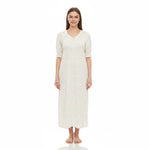 A woman modeling a long-sleeved, knee-length nightgown with a small floral print on a cream background, standing against a plain white studio background.