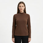 A woman modeling a brown mock neck long-sleeve top against a plain white background.
