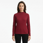 A woman modeling a long-sleeve mock neck knit top in deep burgundy, paired with black pants, against a plain white studio background.