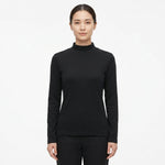 A woman modeling a black long-sleeve mock neck top against a plain white studio background.