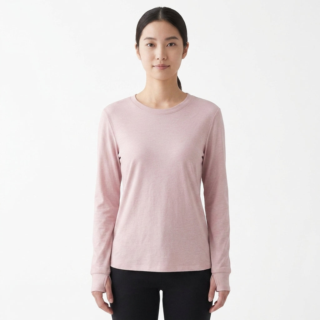 A woman modeling a light pink long-sleeve crewneck shirt against a plain white studio background.