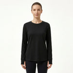 A woman modeling a black long-sleeve crewneck top against a plain white studio background.
