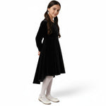 JOANNA FASHION girls black velvet high-low dress with sparkling bodice and long sleeves, worn with white tights.