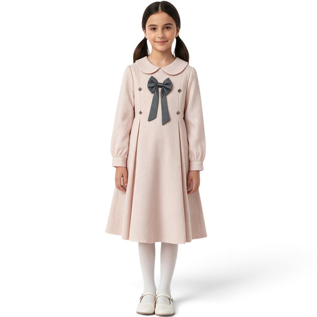 JOANNA FASHION girl wearing a blush pink long-sleeve dress with a Peter Pan collar, bow detail, and pleated skirt.