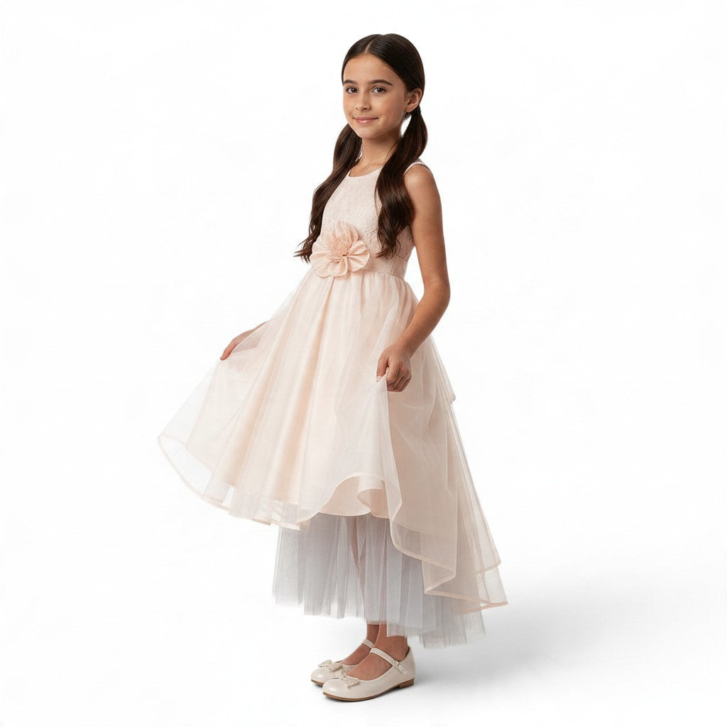 JOANNA FASHION girl wearing a blush pink sleeveless formal dress with lace bodice, floral waist, and high-low tulle skirt
