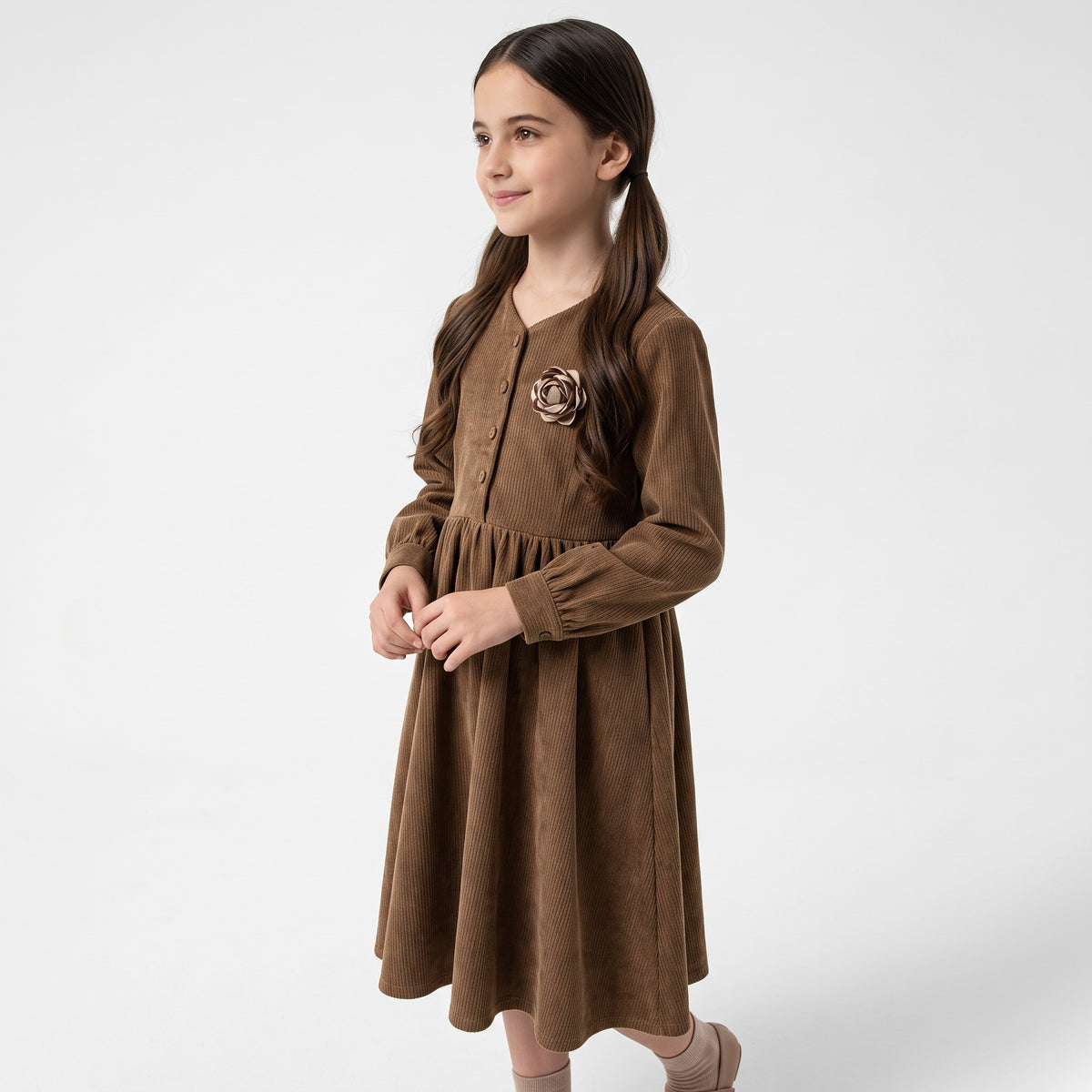 A young girl wearing a JOANNA FASHION brown corduroy long sleeve dress with a rose floral appliqué on the chest.