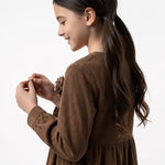 JOANNA FASHION brown corduroy long sleeve dress with floral appliqué on a young girl in profile view