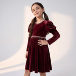 JOANNA FASHION girl wearing a deep burgundy velvet dress with puff sleeves and pearl-style trim at the neckline and waist