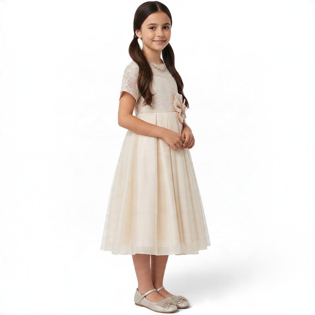 JOANNA FASHION girl wearing a champagne formal dress with a lace bodice, tulle skirt, and a large waist flower.