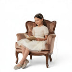 JOANNA FASHION cream party dress with puff sleeves and tulle skirt worn by a girl reading in a velvet armchair