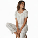 JOANNA FASHION floral pajama set with puff sleeves, lace trim, and ribbon bow on a woman sitting on a wooden stool.