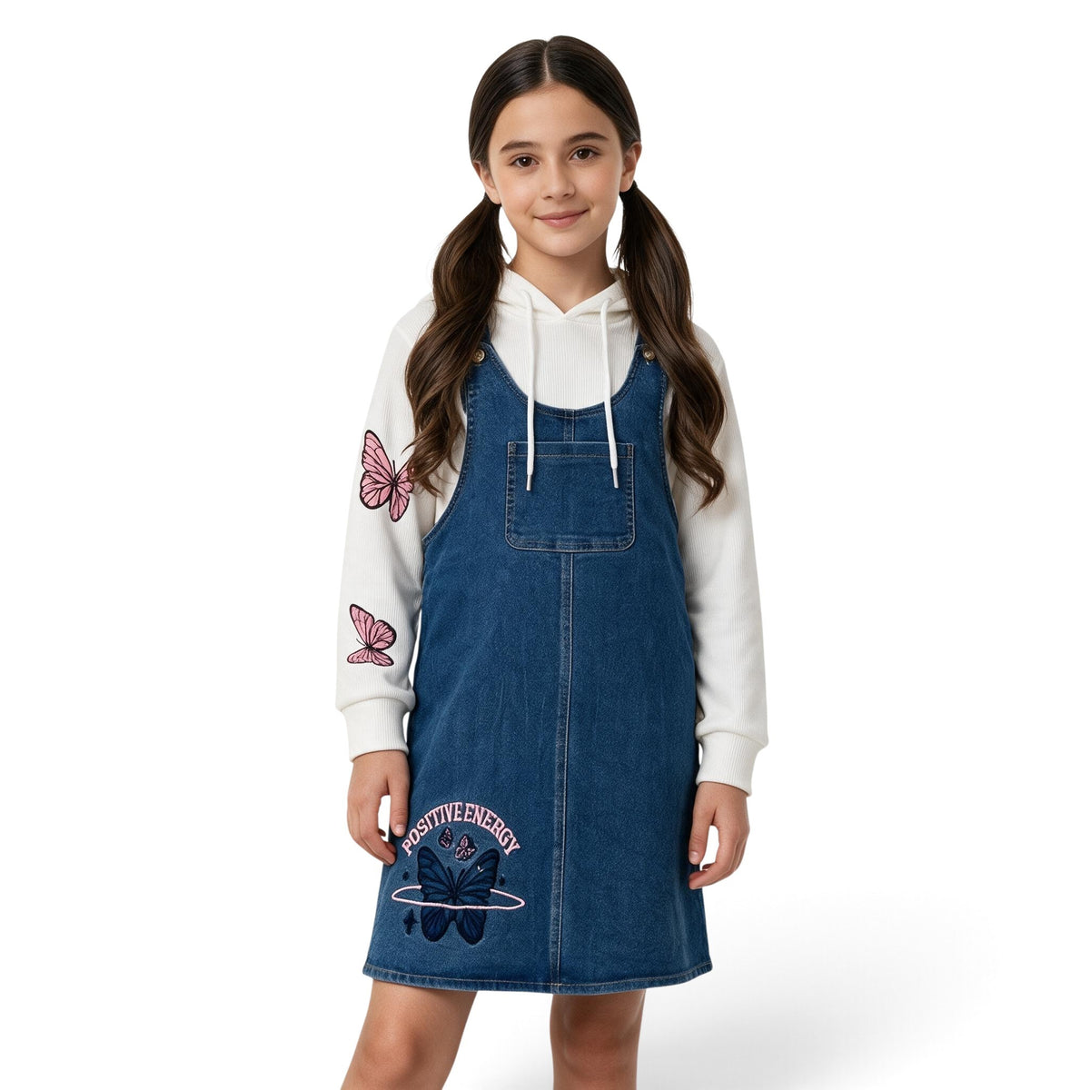 JOANNA FASHION girls blue denim pinafore dress worn over a white long-sleeve hoodie with pink butterfly graphics.