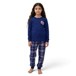 A young girl wearing a JOANNA FASHION blue long-sleeve henley pajama top with a collegiate logo and plaid pants.