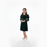 JOANNA FASHION girl wearing a dark green velvet dress with puff sleeves and pearl trim, standing on a white background.