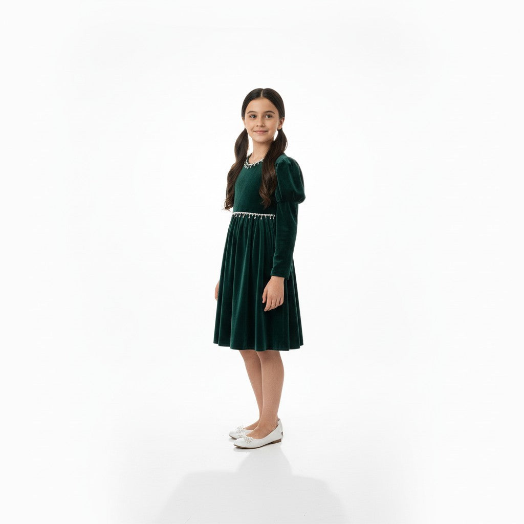 JOANNA FASHION girl wearing a dark green velvet dress with puff sleeves and pearl trim, standing against white background