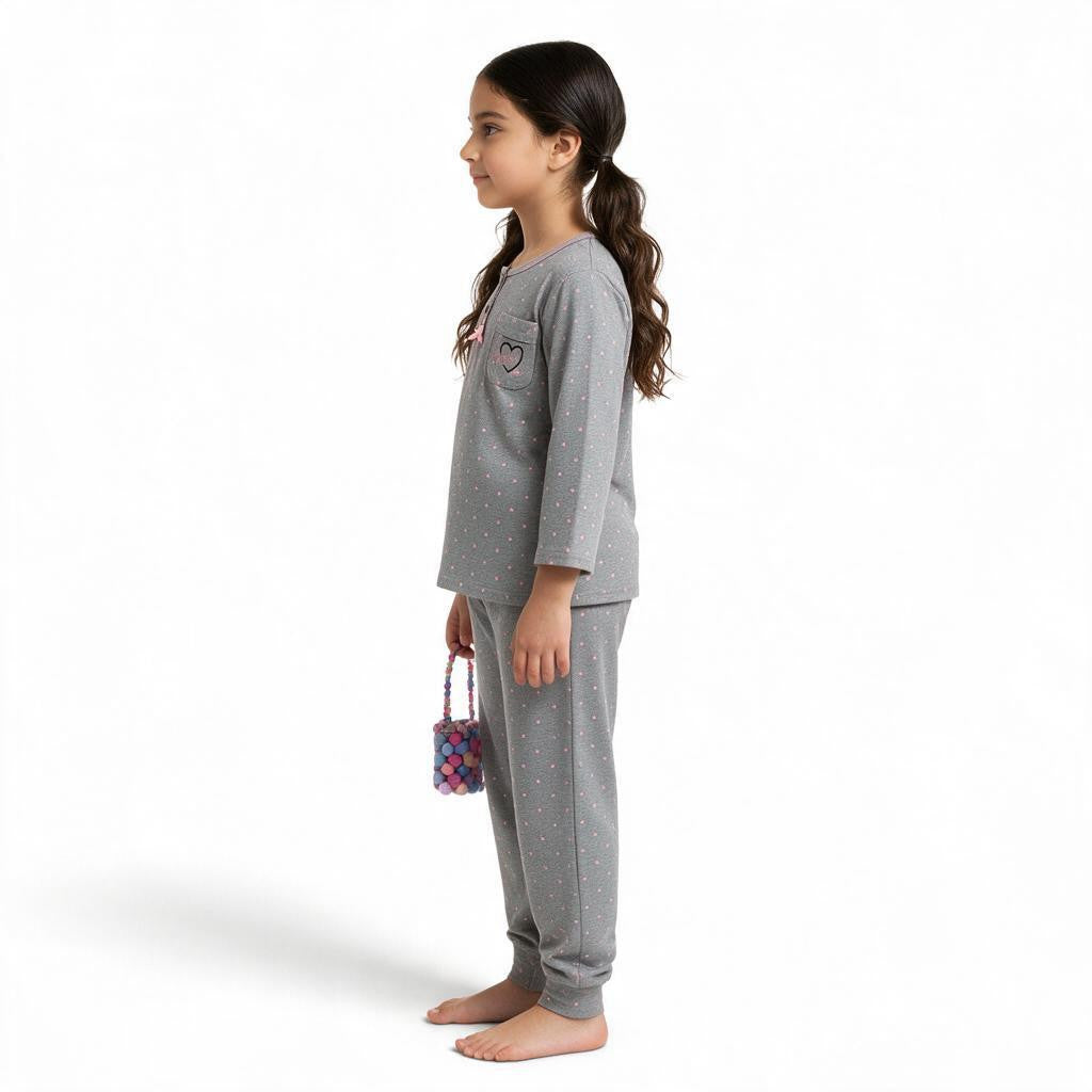 A girl wearing a JOANNA FASHION grey polka-dot long-sleeve pajama set with a heart-pocket top and ribbed cuffs.