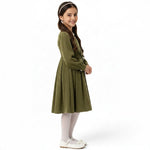 A girl wearing a JOANNA FASHION olive green corduroy long-sleeve pleated dress with a pearl-embellished butterfly waist.