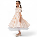 JOANNA FASHION girl wearing a peach satin formal dress with puff sleeves, pearl accents, and a white tulle underskirt.