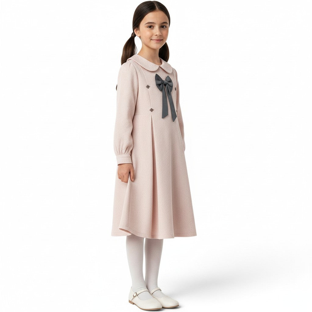 JOANNA FASHION girl wearing a pale pink textured long-sleeve dress with a Peter Pan collar and grey bow detail.