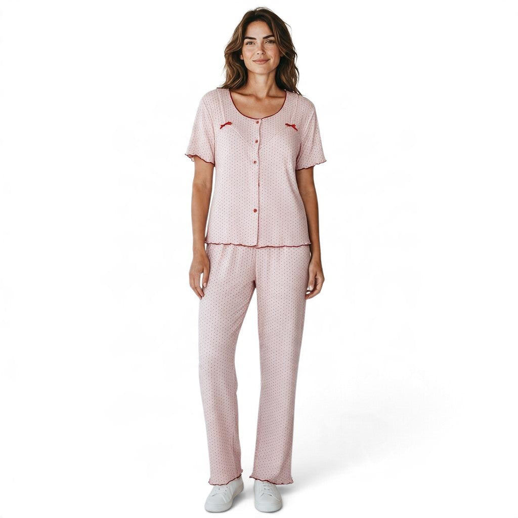 A model wearing a JOANNA FASHION light pink polka dot pajama set with lettuce-edge trim and bow accents.