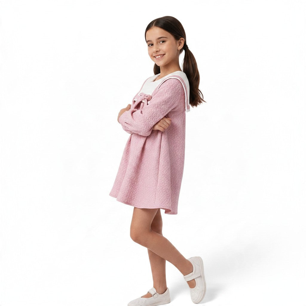 JOANNA FASHION girl wearing a pink textured A-line dress with a white sailor collar and bow detail