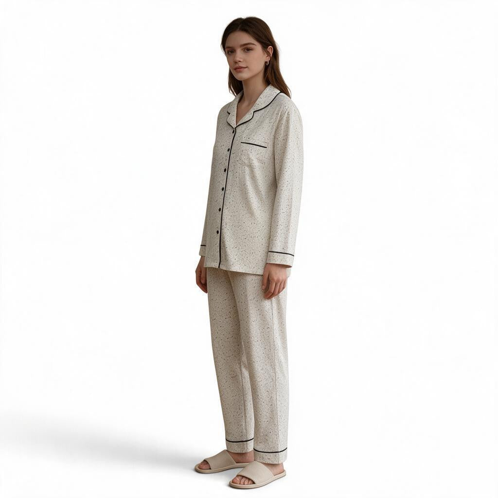 A model wearing a JOANNA FASHION speckled print long-sleeve button-down pajama set with black piping and trousers.